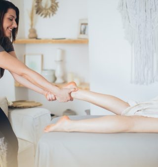Massagista fazendo massagem em cliente que está deitada de bruços