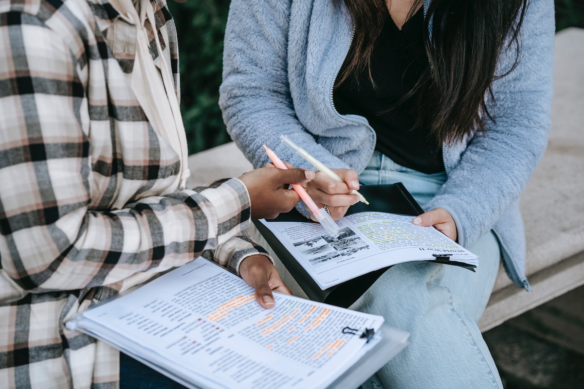 Duas alunas lendo apostilas escaneadas e com destaques de marca-texto 