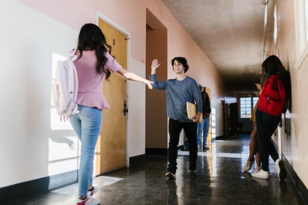 Dois alunos passam pelo corredor de uma escola SENAI Presidente Prudente 2024, e fazem gesto de que vão tocar as mãos