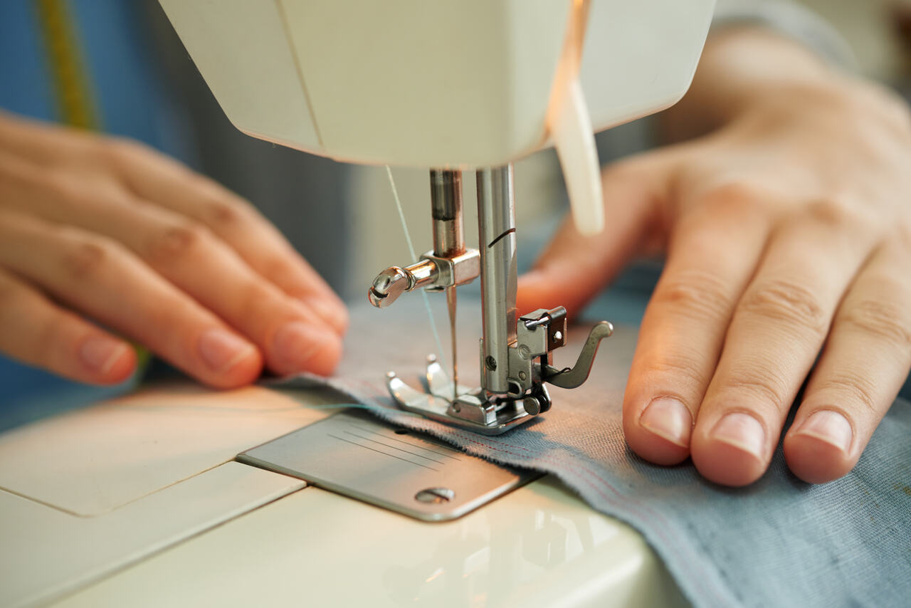 Mulher costurando peça em máquina de costura 