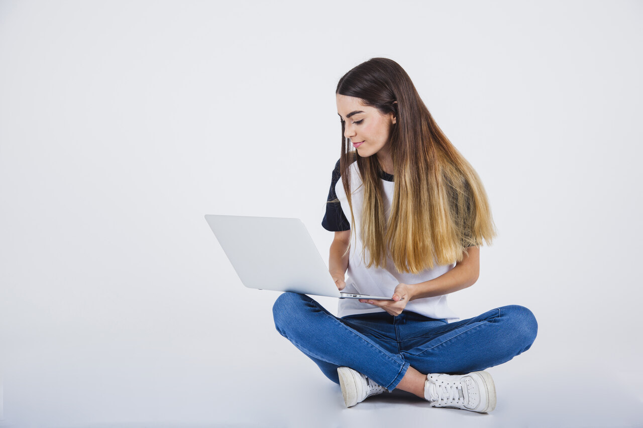 jovem sentada no chão trabalhando com computador 