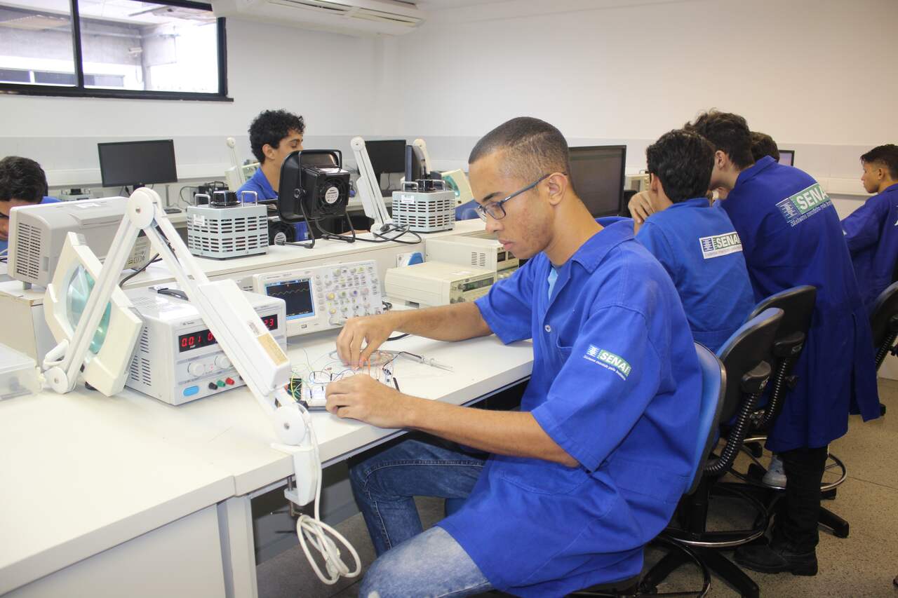 Alunos de cursos técnicos sentados em mesas de laboratório do Senai SE 