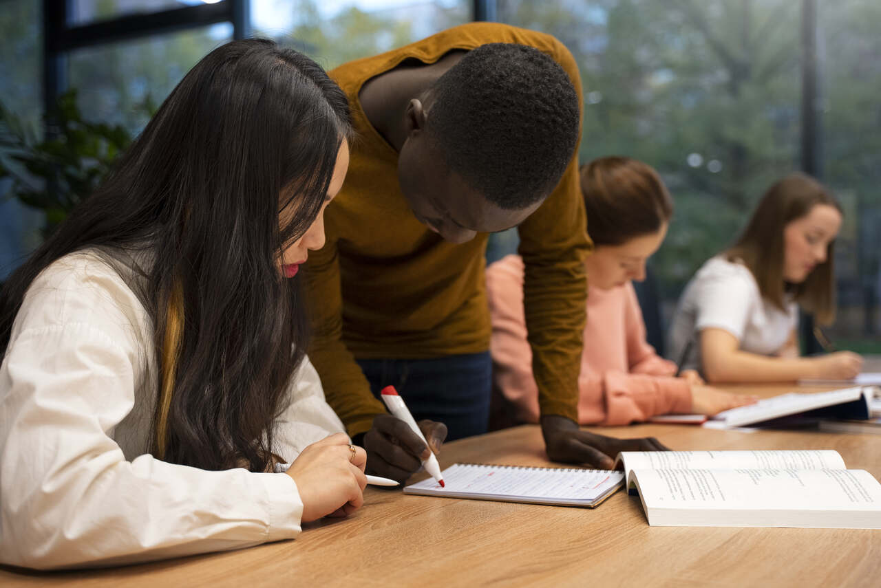 Jovens estudando em sala de aula com cadernos, lápis e canetas
