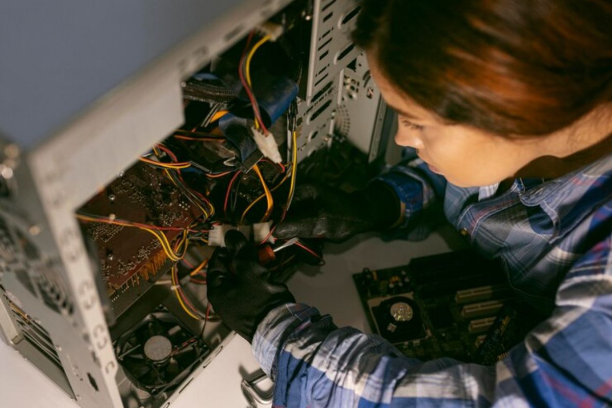 Uma estudante mexendo em um computador aberto. Ela está cursando o Curso Técnico Manutenção e Suporte Informática SENAI 2025