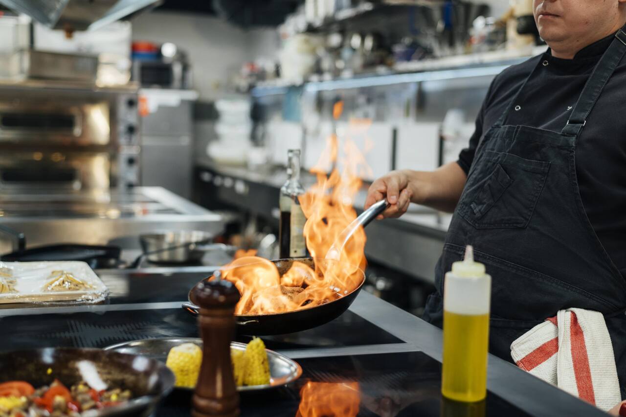 Chef flamba algo em uma frigideira 