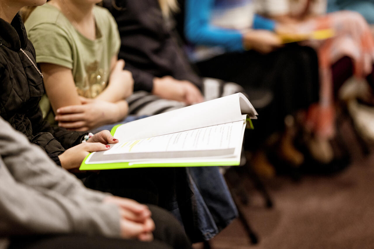 Close das mãos de pessoa segurando livro em meio a grupo de estudo 