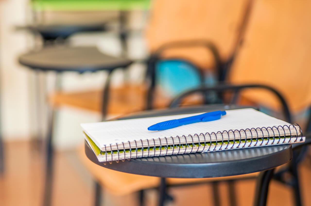 Close de um caderno com uma caneta em cima sobre uma mesa