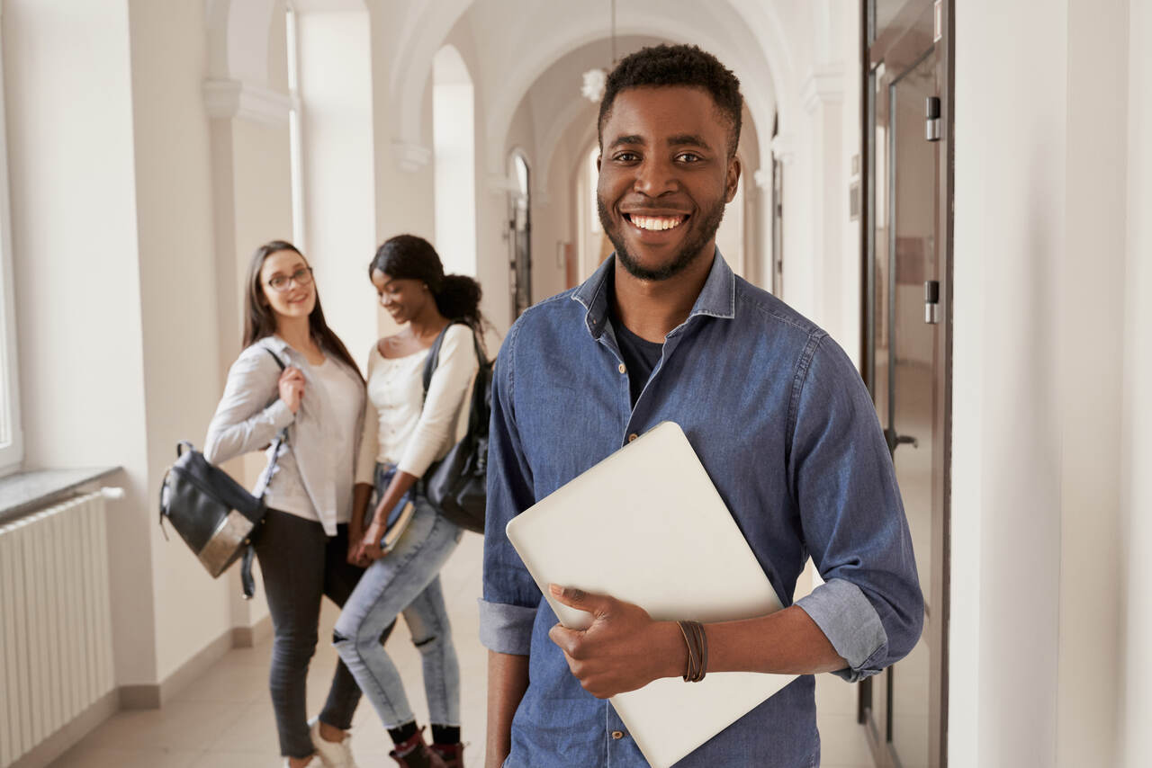 Jovem estudante no corredor de instituição de ensino com colegas ao fundo