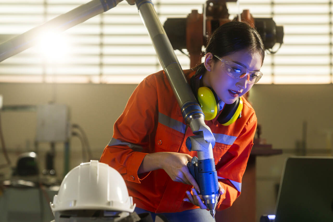 Jovem trabalha com braço robotico em industria 