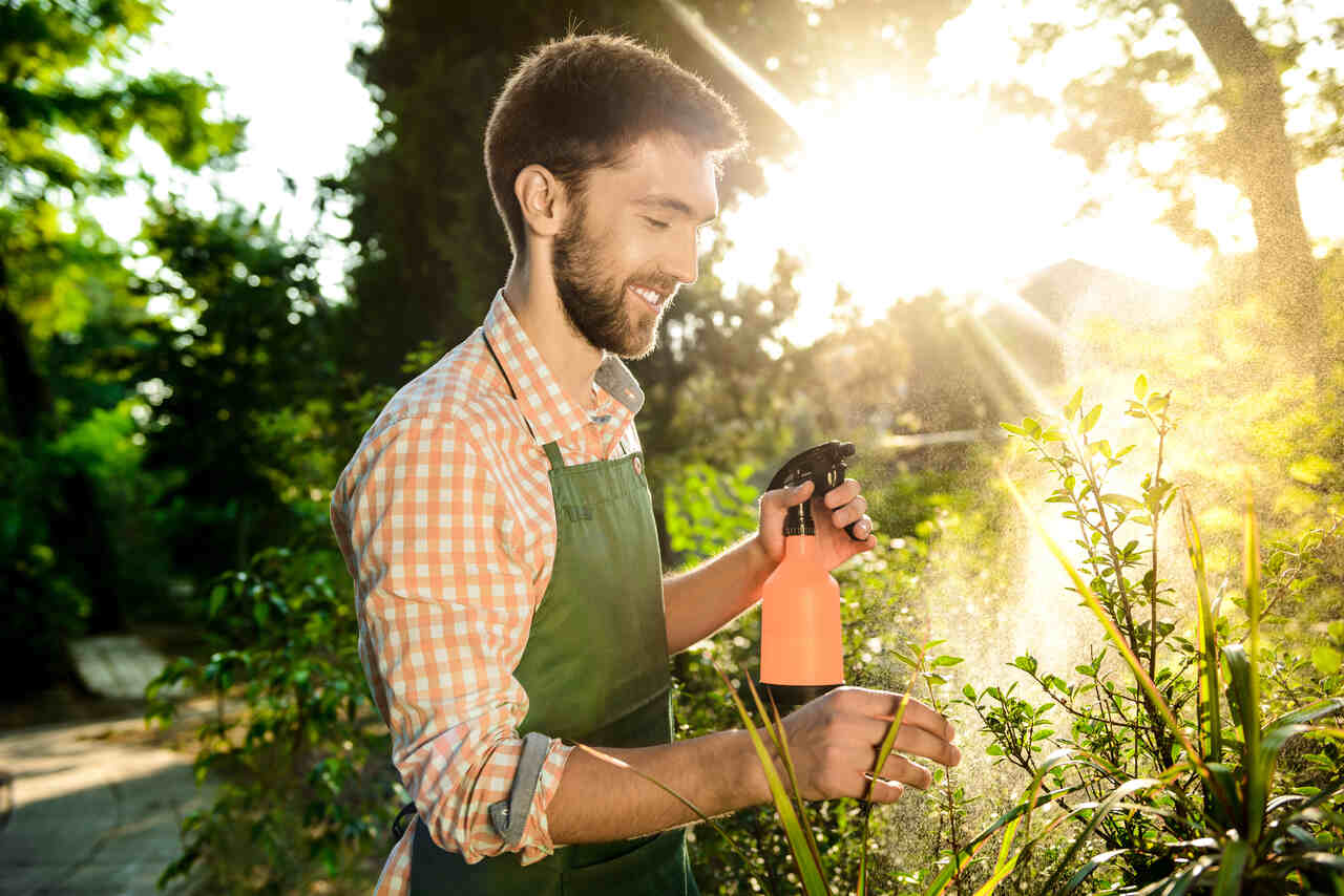 Jardineira aplica produto contra pragas em plantas 