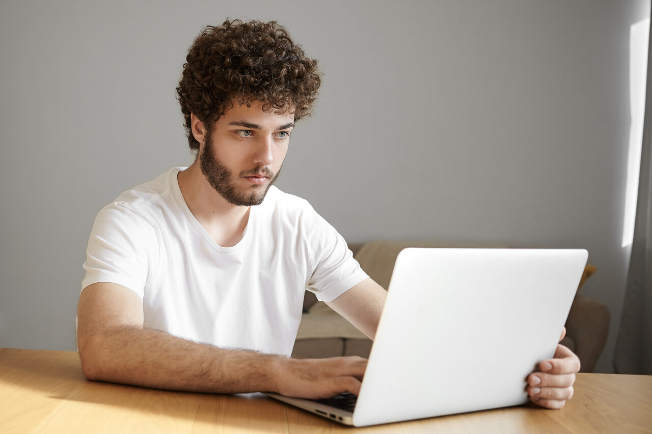 Jovem trabalha em seu notebook atentamente 