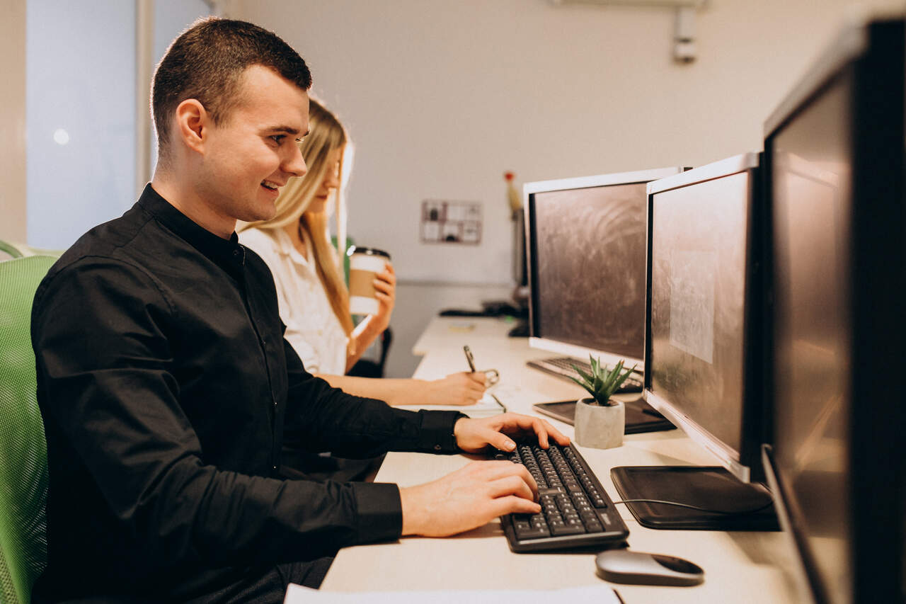 Jovem trabalhando em seu computador em empresa de TI