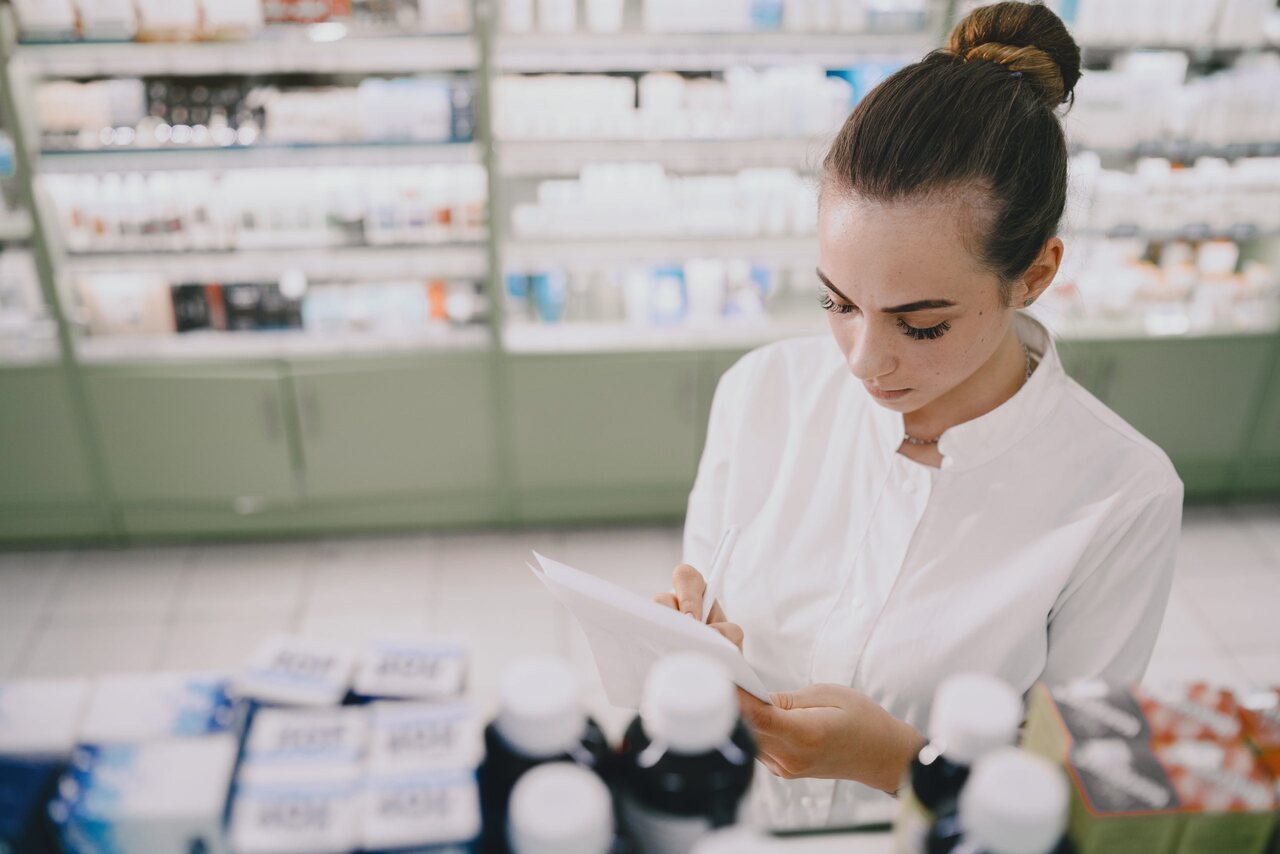 Atendente de farmácia confere estoque de medicamentos 