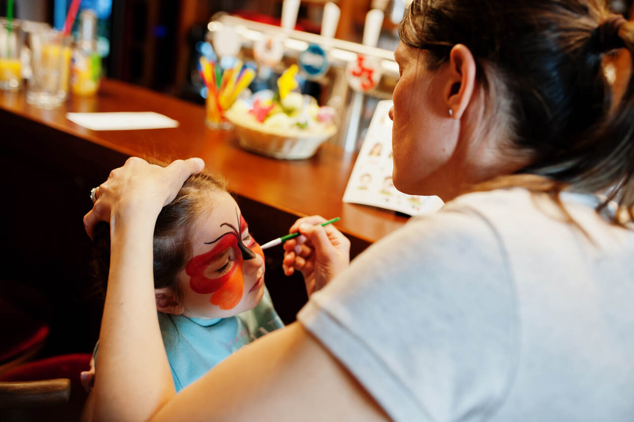 Profissional faz pintura artística em rosto de menina 