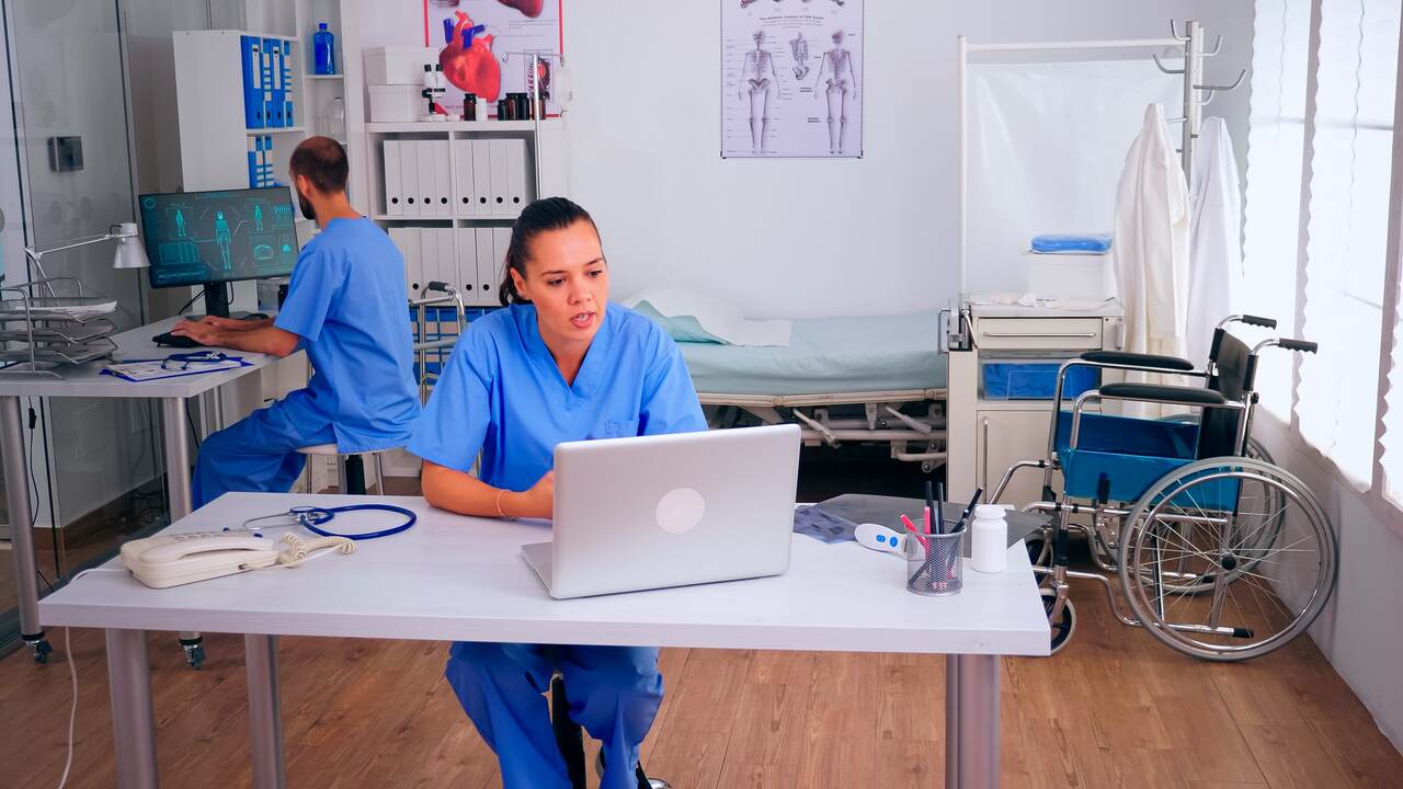 Auxiliar de enfermagem atualiza dados de pacientes em computador da enfermaria