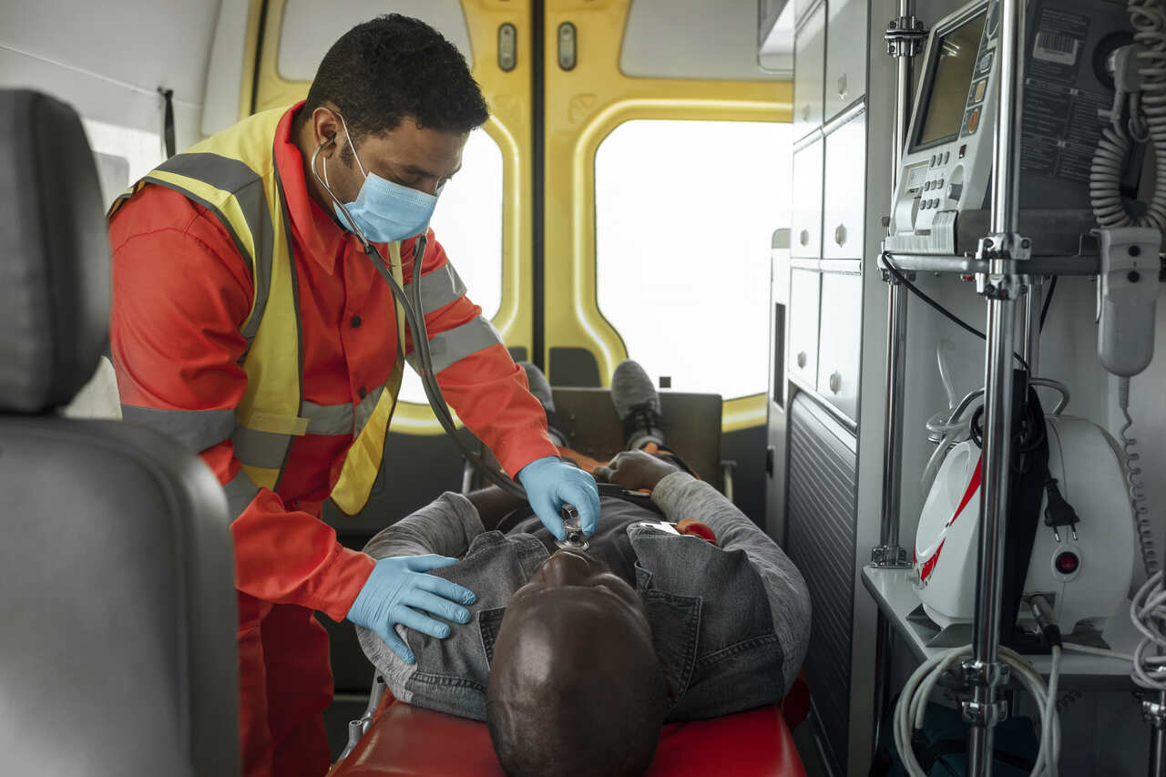 Socorrista verifica sinais vitais de paciente dentro de ambulância 